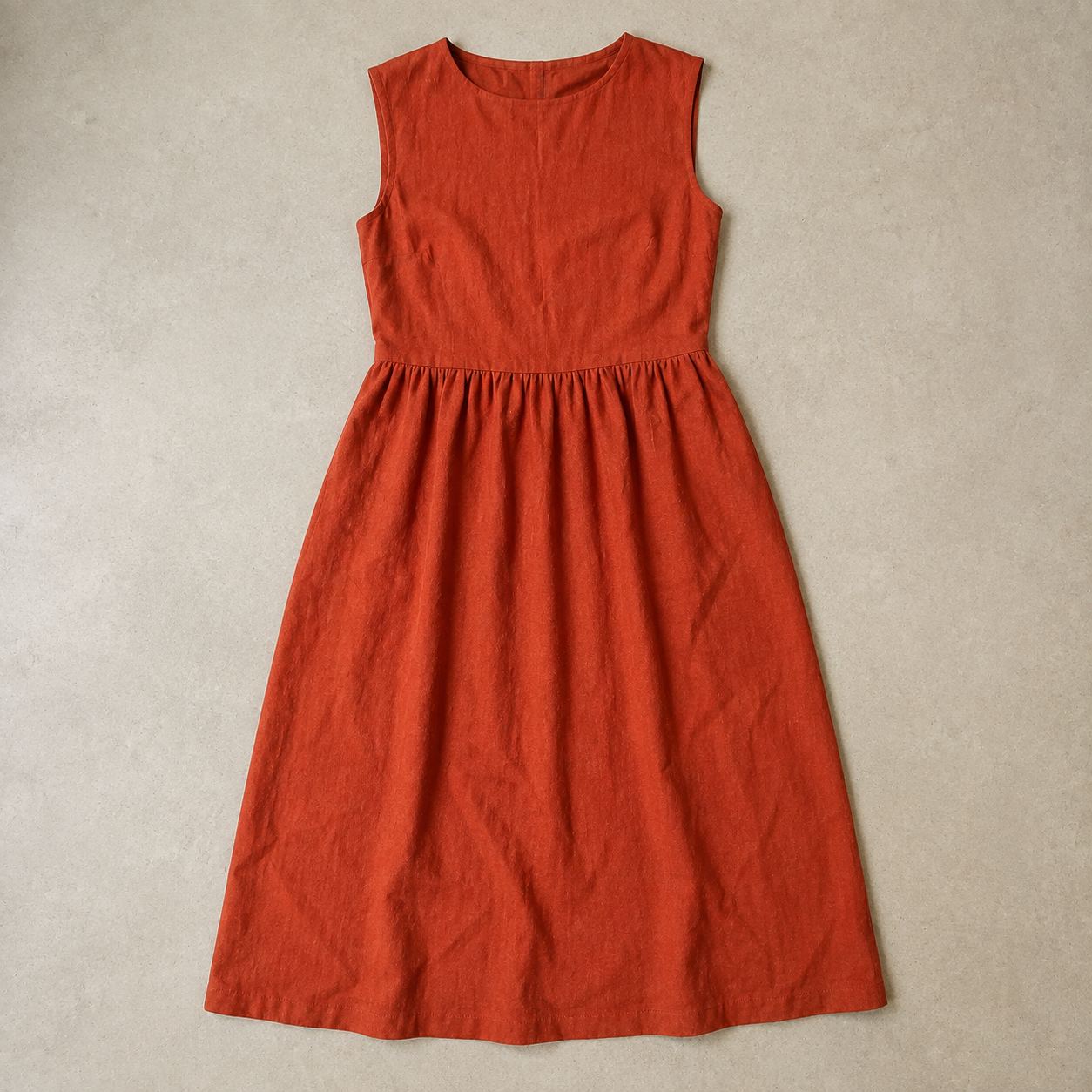 Vestido terracota extendido sobre una superficie neutra